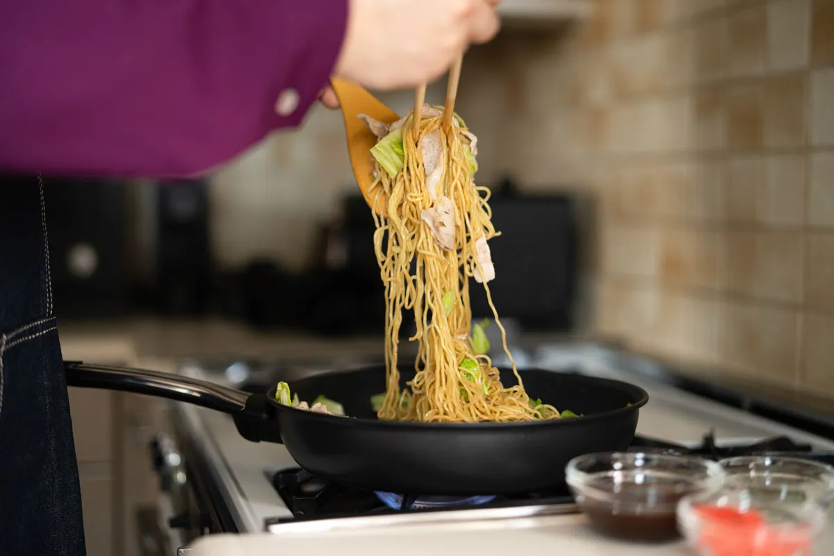 フライパンで焼きそばの麺を混ぜる