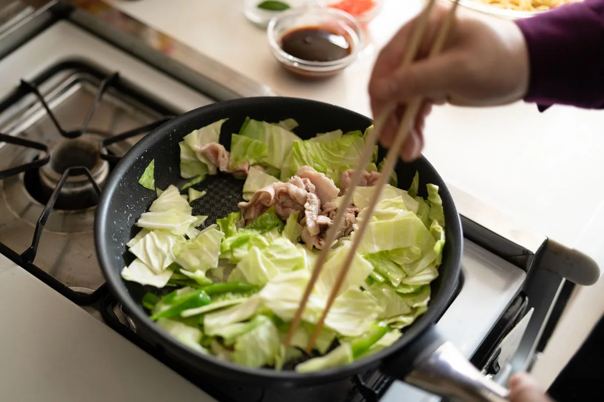 フライパンで豚バラ肉・キャベツ・ピーマンを炒める