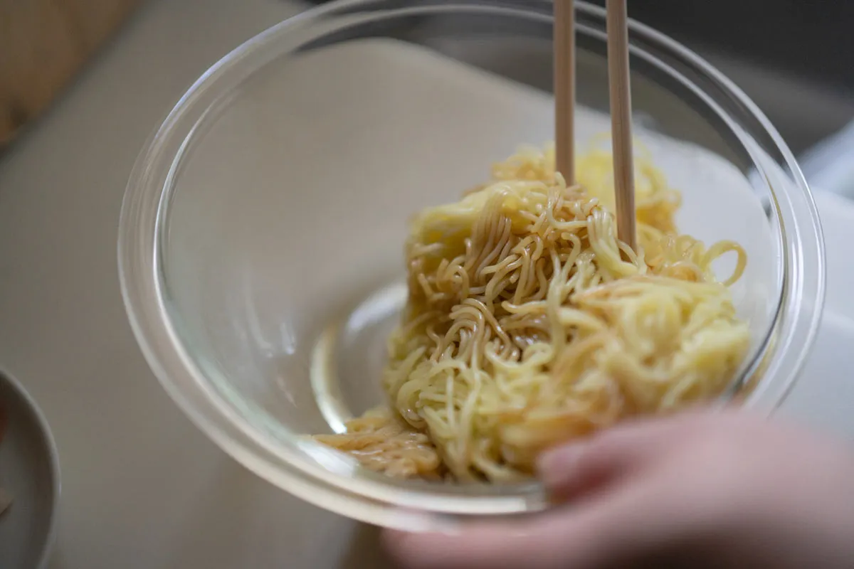 焼きそばの麺にしょうゆで下味をつけて混ぜる