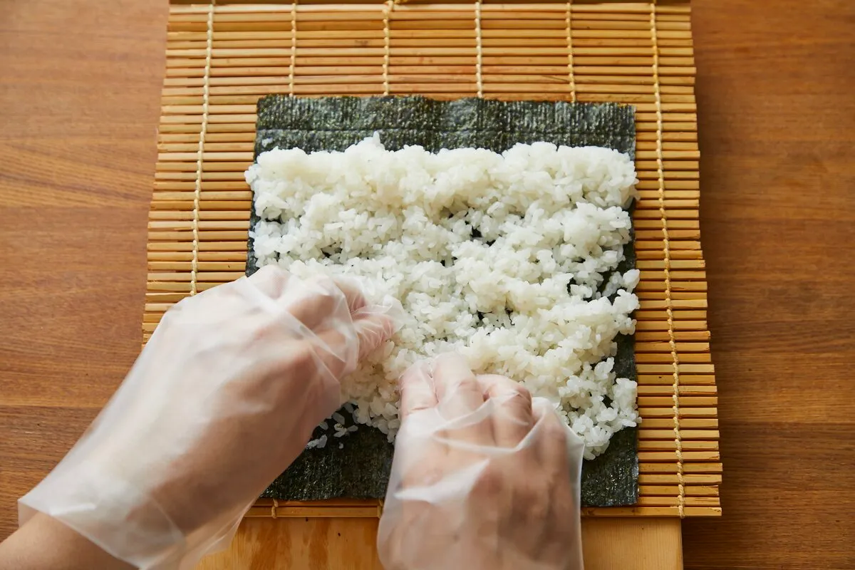 均一に平らに広げることが、きれいに仕上げる最大のポイント。すしめしが手にくっつくときは、エンボスタイプの使い捨て手袋がおすすめ。 または、指先を手酢(水10:酢1程度の割合で混ぜる)でぬらすとすしめしが広げやすい。